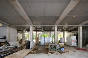 Ruimte in aanbouw aan de Karel du Jardinstraat met bouwmaterialen, machines en betonnen pilaren.